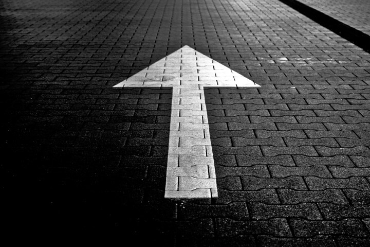 A picture of a white coloured arrow on a brick pathway.